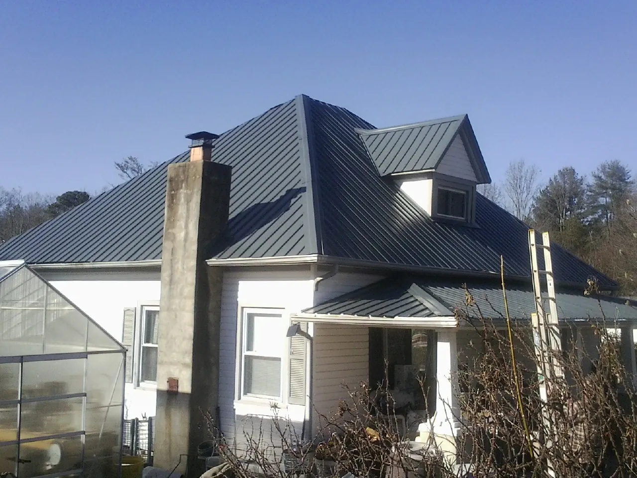 Dark blue standing seam metal roof on a white farmhouse with dormer — Slate & Tile Roof Repair by Roofing Brothers in Dayton