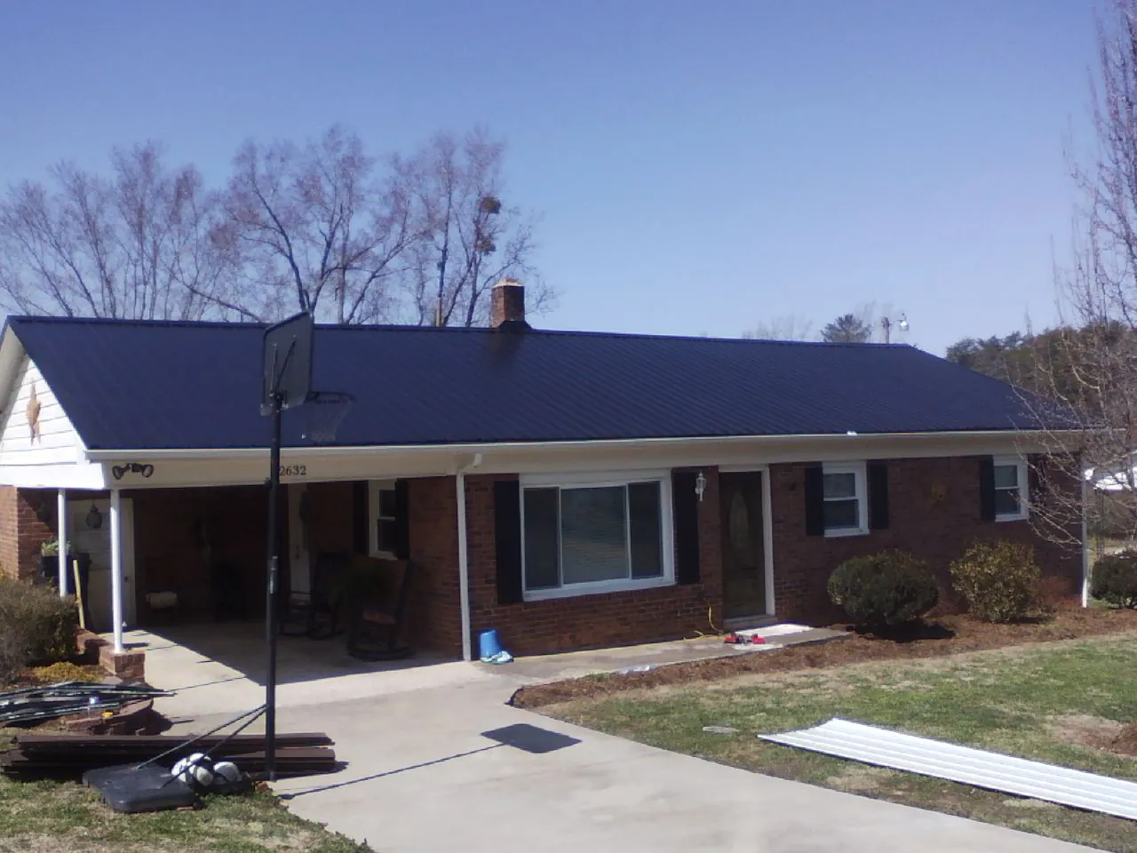 Finished dark blue metal roof on a brick ranch with a carport in Dayton