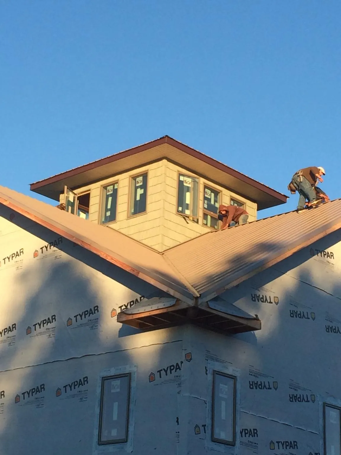 Roofers working around a rooftop cupola on a new metal roof at sunset — Roof Waterproofing in Dayton by Roofing Brothers